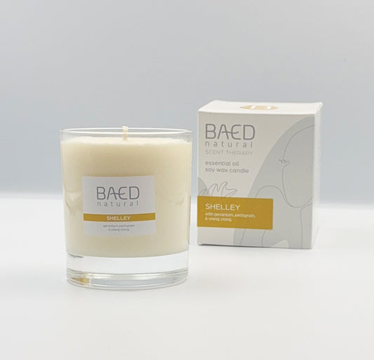 SHELLEY SOY WAX CANDLE IN CLEAR GLASS JAR WITH WHITE LABEL AND BOX IN THE BACKGROUND